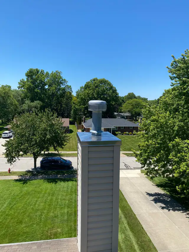 A reflective metal chase cover fitted across the top of a sided chimney chase around its round vent