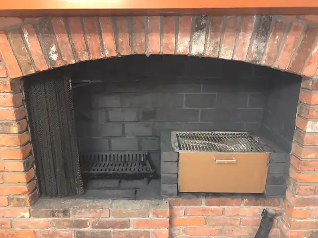 A cleaned firebox with a cast iron grate, an ash pit door and an intact damper, framed by an arched brick surround