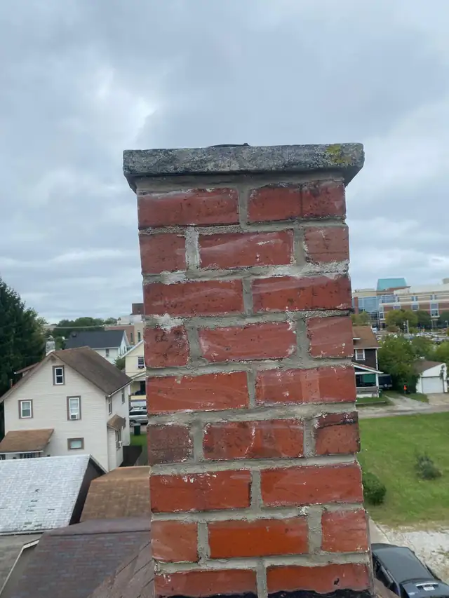 The same brick chimney stack after repointing, with the joints cut out and refilled with fresh, fully packed mortar